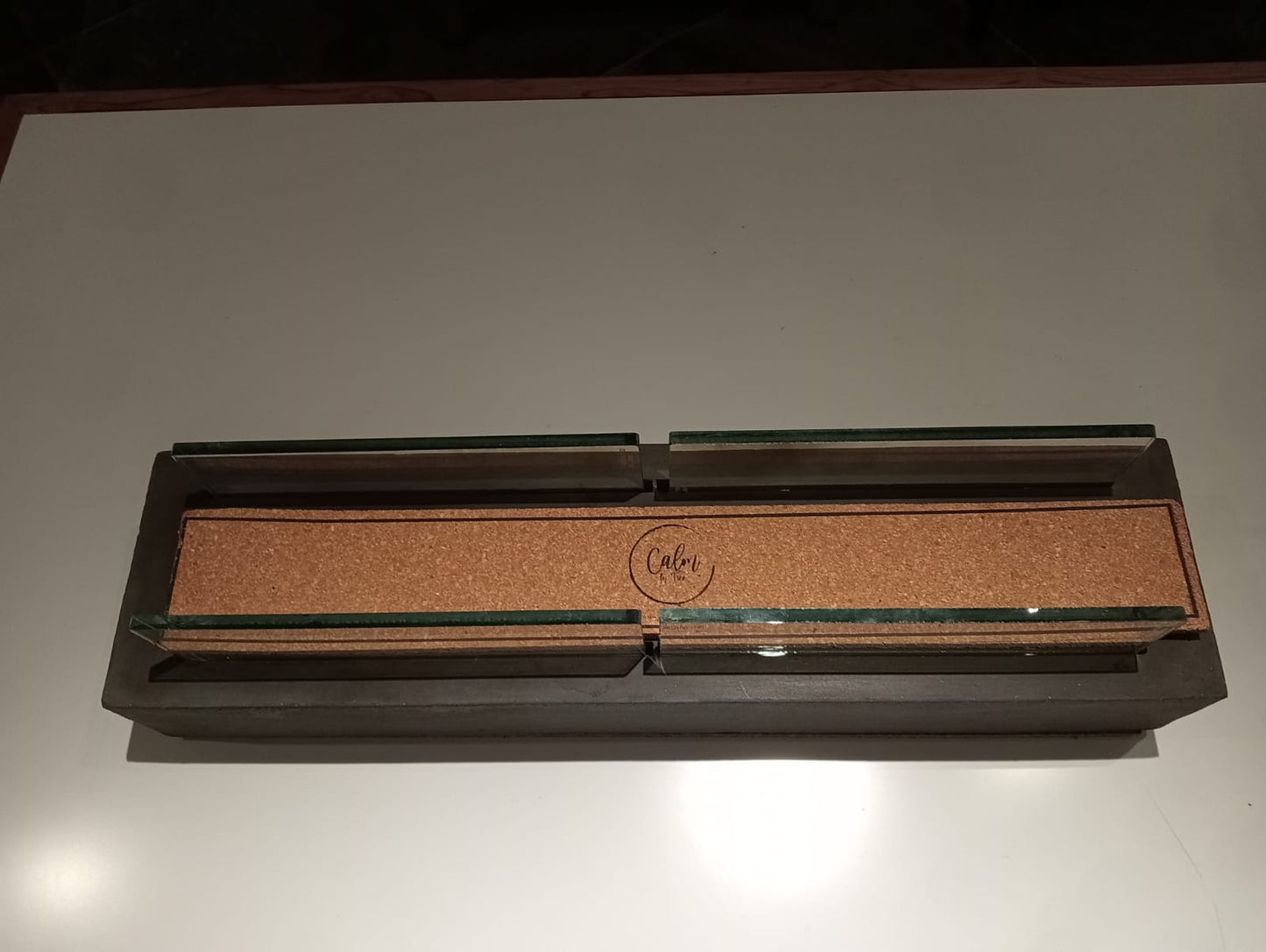 Close‑up view of The AllForge’s metal frame and safety glass cover, with reflections of flame